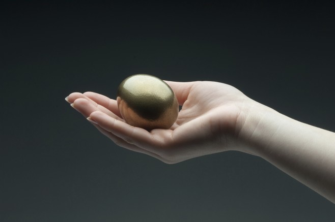 Woman's hand holding a golden egg
