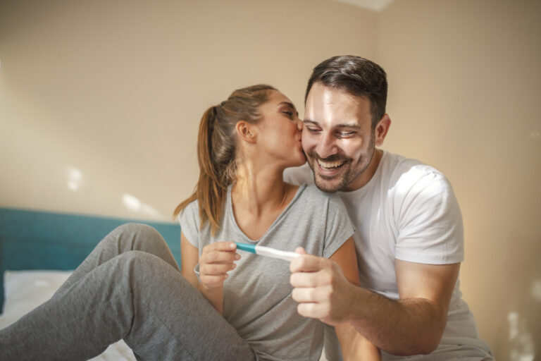 happy couple with at home holding positive pregnancy test