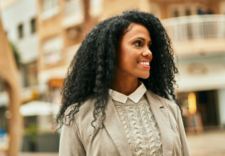 happy woman in blazer stood outside looking up